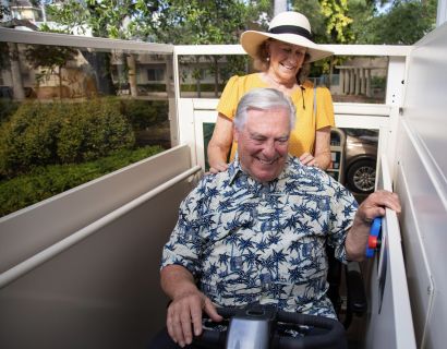 Man and woman using a platform lift. both smiling. 